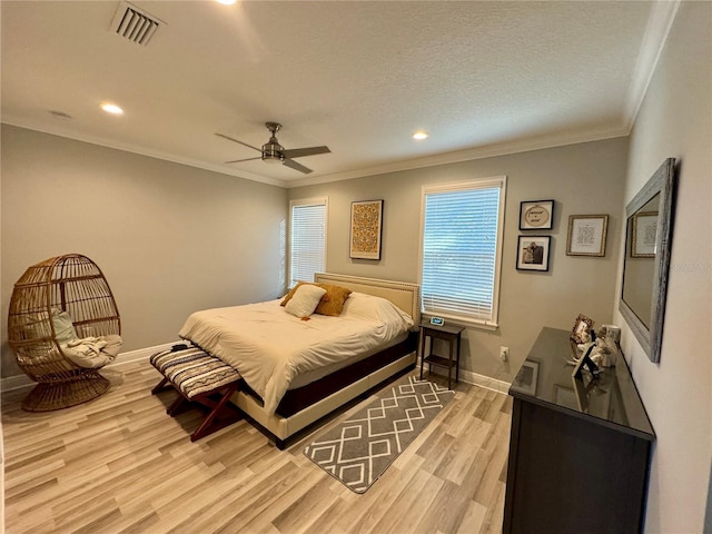 bedroom with light wood-type flooring, baseboards, visible vents, and ornamental molding