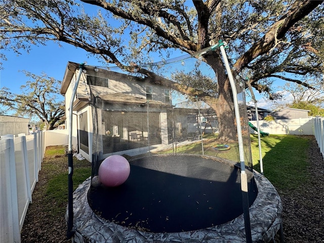 view of property exterior featuring a yard, a trampoline, and a fenced backyard