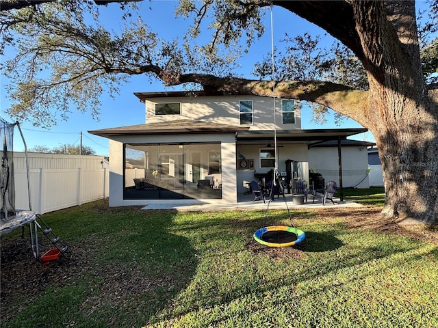 back of house with fence, a sunroom, a yard, stucco siding, and a patio area