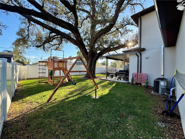 view of yard featuring a playground, a patio, central AC, and a fenced backyard