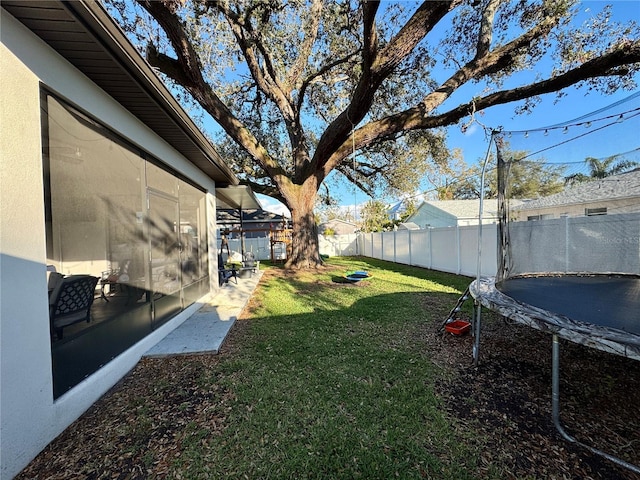 view of yard featuring a trampoline and a fenced backyard