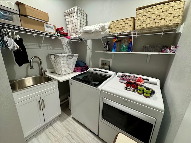 washroom with light wood-style floors, cabinet space, a sink, and washing machine and clothes dryer