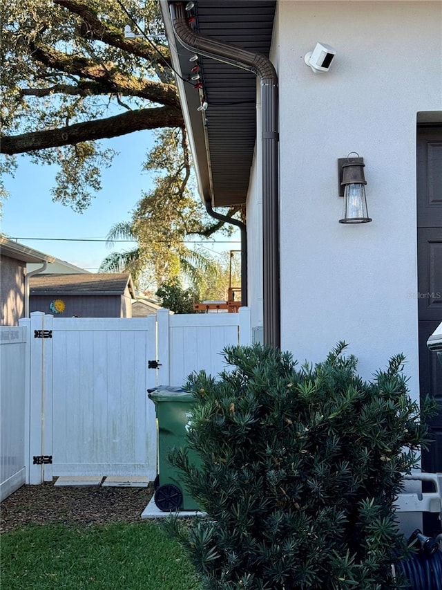 view of side of property with a gate, fence, and stucco siding