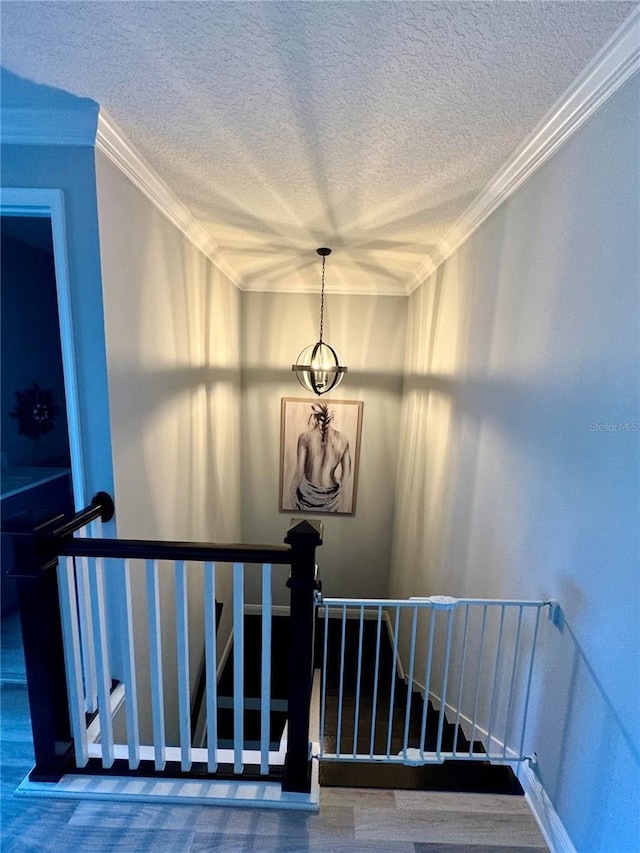 stairway with a textured ceiling, an inviting chandelier, and crown molding