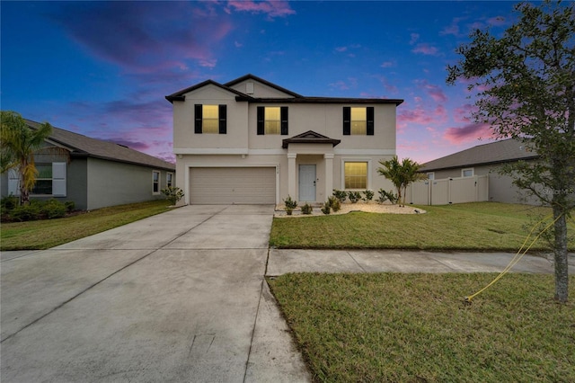 traditional-style house featuring concrete driveway, an attached garage, fence, a front lawn, and stucco siding