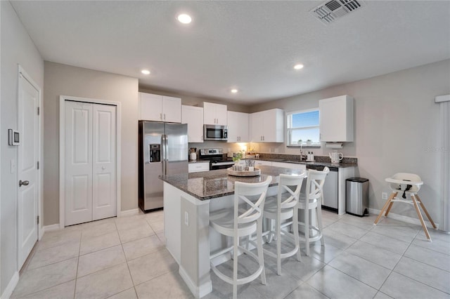 kitchen with stainless steel appliances, visible vents, white cabinets, a kitchen island, and light tile patterned flooring