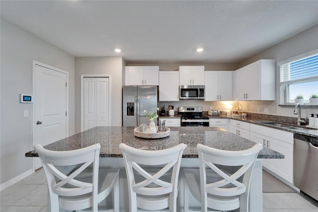 kitchen featuring stainless steel appliances, white cabinets, a sink, and a kitchen island