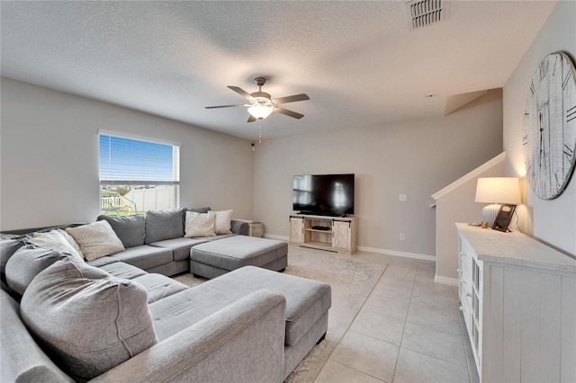 living area featuring light tile patterned floors, ceiling fan, visible vents, and a textured ceiling