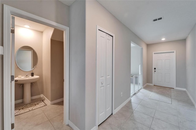 hall with visible vents, baseboards, and light tile patterned floors