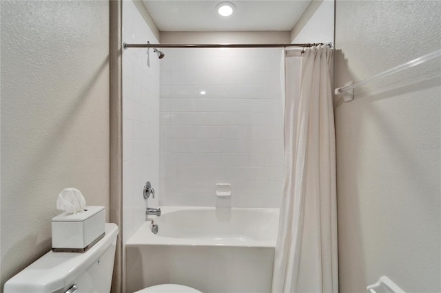 bathroom with toilet, shower / bathtub combination with curtain, and a textured wall