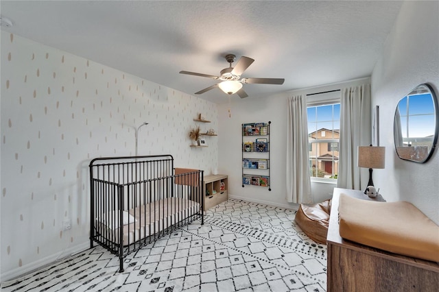 bedroom featuring multiple windows, a crib, baseboards, and wallpapered walls