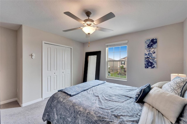 bedroom featuring a closet, light colored carpet, a ceiling fan, a textured ceiling, and baseboards