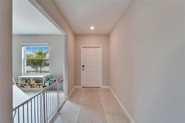 doorway with light tile patterned flooring and baseboards