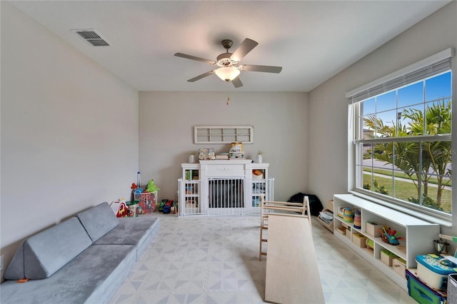 rec room featuring a ceiling fan, visible vents, a fireplace, and light floors