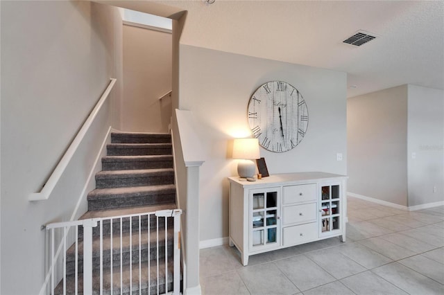 staircase with visible vents, baseboards, and tile patterned floors