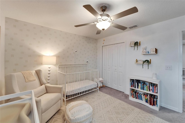 carpeted bedroom with wallpapered walls, baseboards, visible vents, a ceiling fan, and a closet