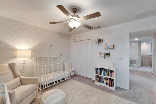 bedroom with wallpapered walls, carpet, visible vents, and a closet