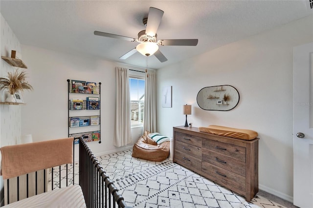 bedroom featuring light carpet, a textured ceiling, baseboards, and a ceiling fan