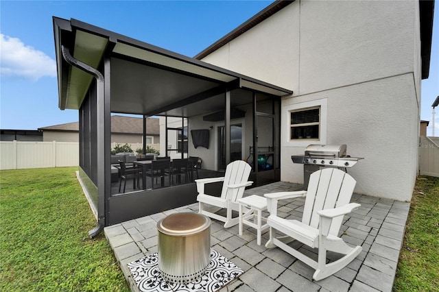 view of patio / terrace featuring fence, a sunroom, and a grill