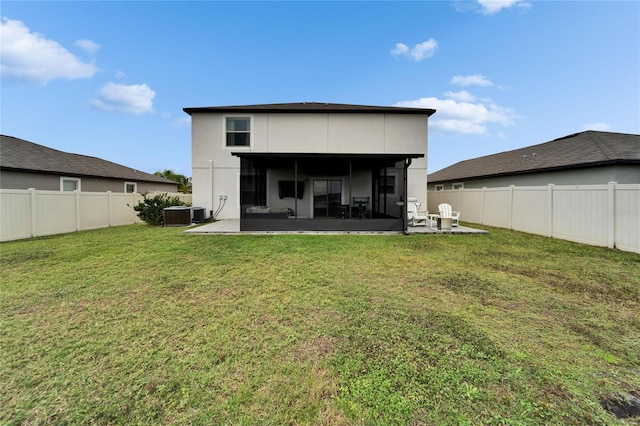 rear view of house featuring a lawn, a sunroom, a fenced backyard, a patio area, and central AC