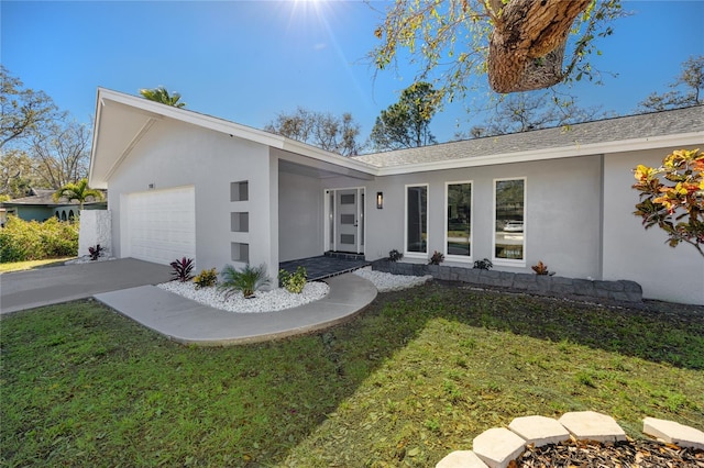 view of front of house featuring a garage, driveway, a front lawn, and stucco siding