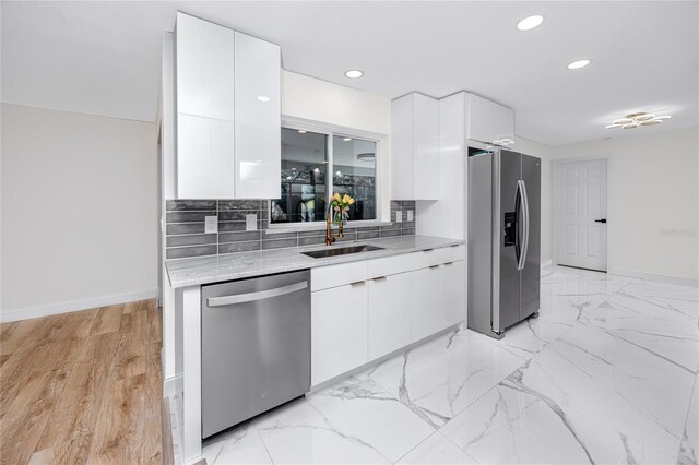 kitchen with stainless steel appliances, a sink, and white cabinets