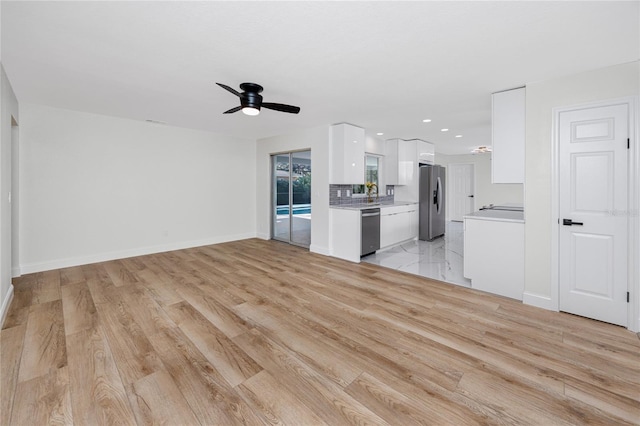 kitchen with baseboards, appliances with stainless steel finishes, light countertops, white cabinetry, and a sink