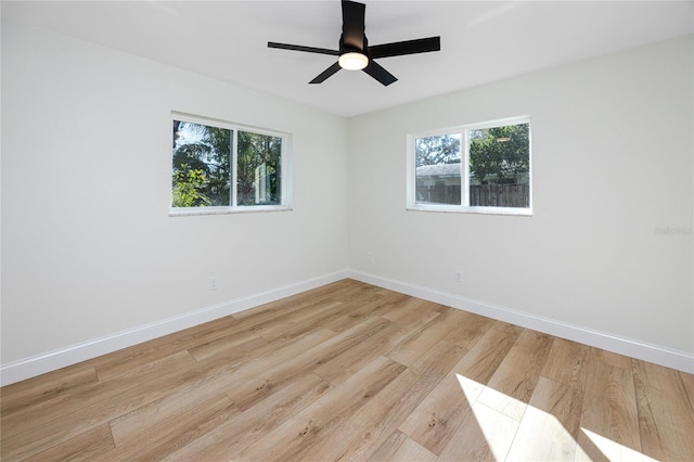 empty room featuring a ceiling fan, light wood-type flooring, and baseboards