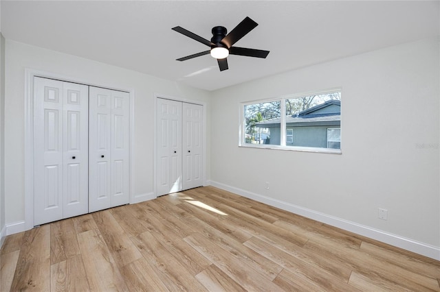 unfurnished bedroom with baseboards, ceiling fan, light wood-style flooring, and multiple closets