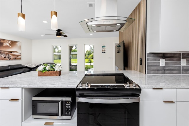 1100 Webb Dr, Clearwater, FL 33755 - kitchen with range with electric stovetop, stainless steel microwave, ventilation hood, white cabinetry, and light stone countertops