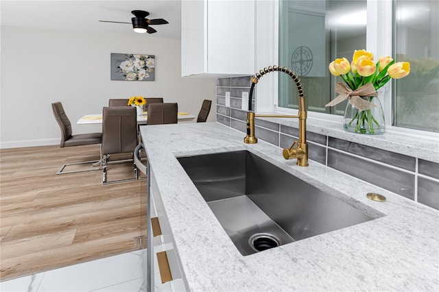 1100 Webb Dr, Clearwater, FL 33755 - kitchen with white cabinetry, light stone countertops, light wood-style flooring, and ceiling fan