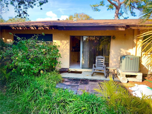 doorway to property featuring cooling unit, a patio area, and stucco siding