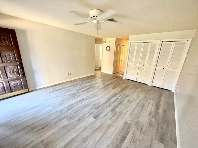 unfurnished bedroom with visible vents, baseboards, ceiling fan, light wood-type flooring, and multiple closets