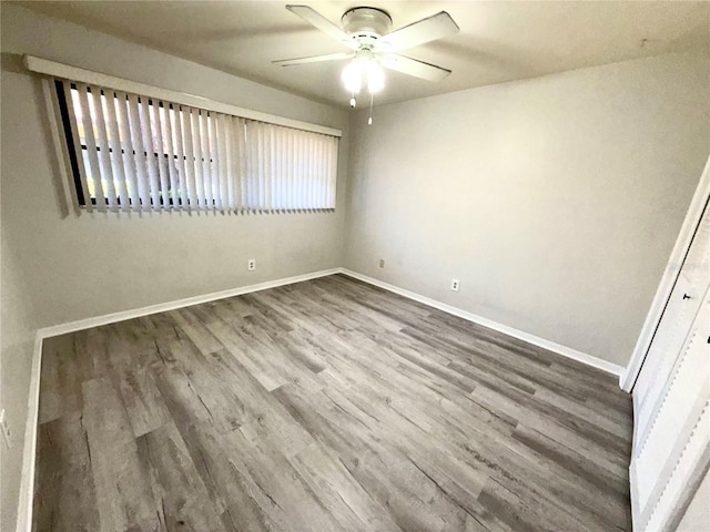 spare room featuring ceiling fan, wood finished floors, and baseboards