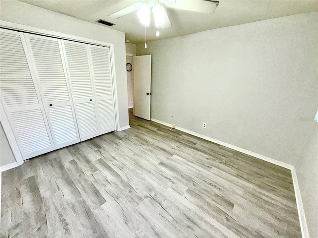 unfurnished bedroom featuring light wood finished floors, a closet, visible vents, ceiling fan, and baseboards