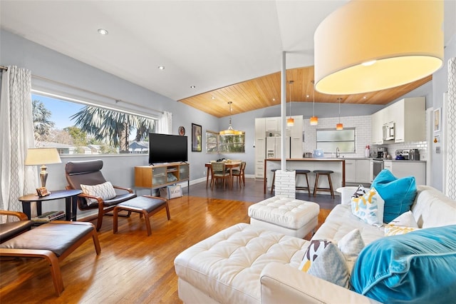 living room with vaulted ceiling, recessed lighting, wood finished floors, and baseboards