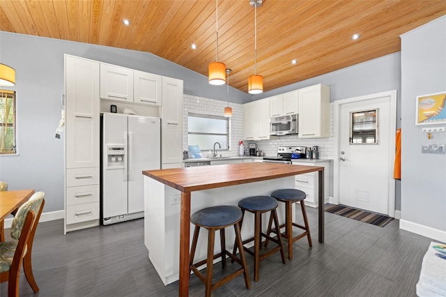 kitchen featuring butcher block counters, a sink, white cabinets, appliances with stainless steel finishes, and tasteful backsplash