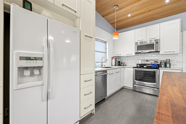 kitchen featuring backsplash, appliances with stainless steel finishes, a sink, butcher block countertops, and wooden ceiling