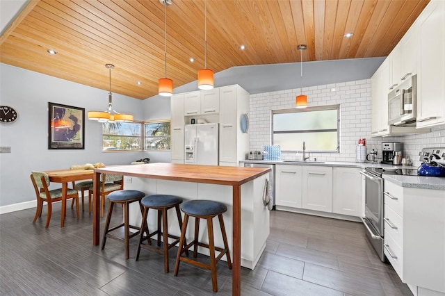 kitchen featuring backsplash, appliances with stainless steel finishes, a kitchen island, wood counters, and a sink