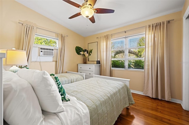 bedroom with cooling unit, wood finished floors, a ceiling fan, baseboards, and vaulted ceiling