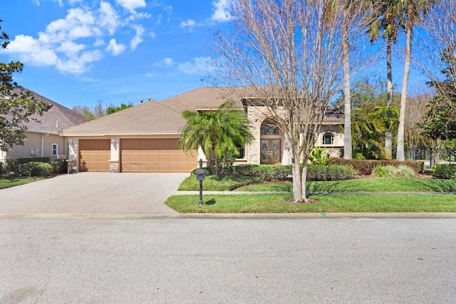 view of front facade featuring a garage, decorative driveway, and stone siding