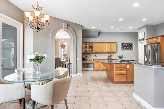 kitchen with stainless steel fridge, a chandelier, arched walkways, and a center island