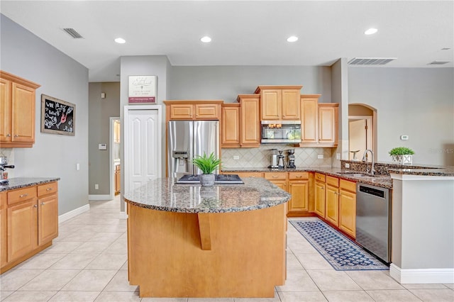 kitchen with arched walkways, stainless steel appliances, visible vents, a sink, and dark stone counters