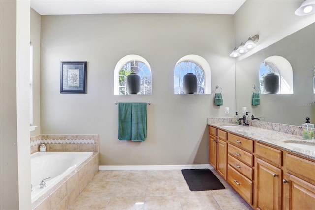 full bath with a garden tub, double vanity, a sink, tile patterned flooring, and baseboards