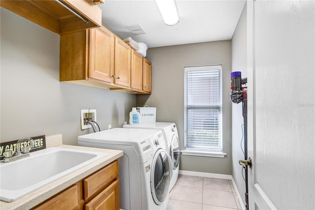 clothes washing area featuring light tile patterned floors, a sink, visible vents, independent washer and dryer, and cabinet space