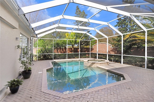 view of pool featuring a pool with connected hot tub, a patio area, and a lanai