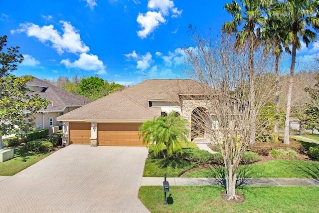 view of front of house with a garage, stone siding, and decorative driveway