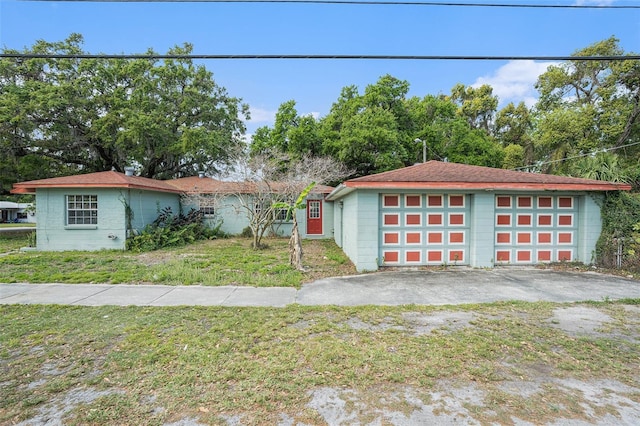 view of front of property featuring a detached garage, concrete block siding, an outdoor structure, and a front lawn