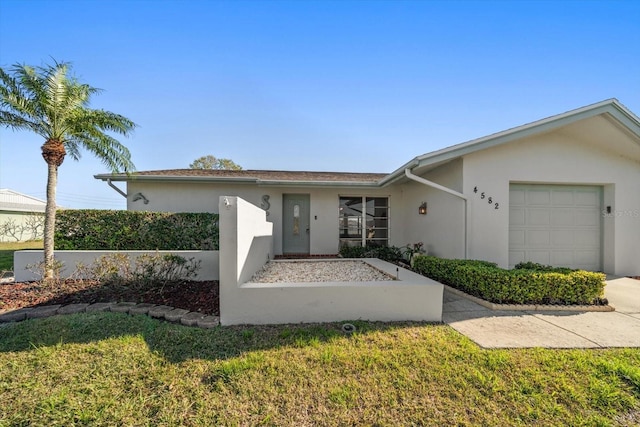 ranch-style home featuring a front yard, an attached garage, and stucco siding