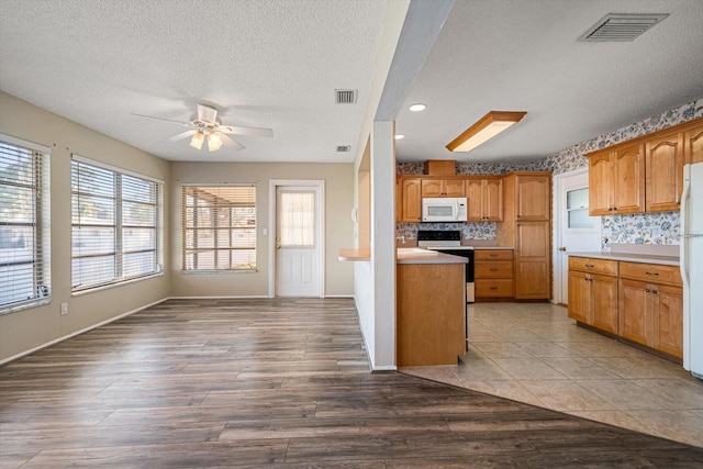 kitchen with white appliances, tasteful backsplash, visible vents, and wood finished floors